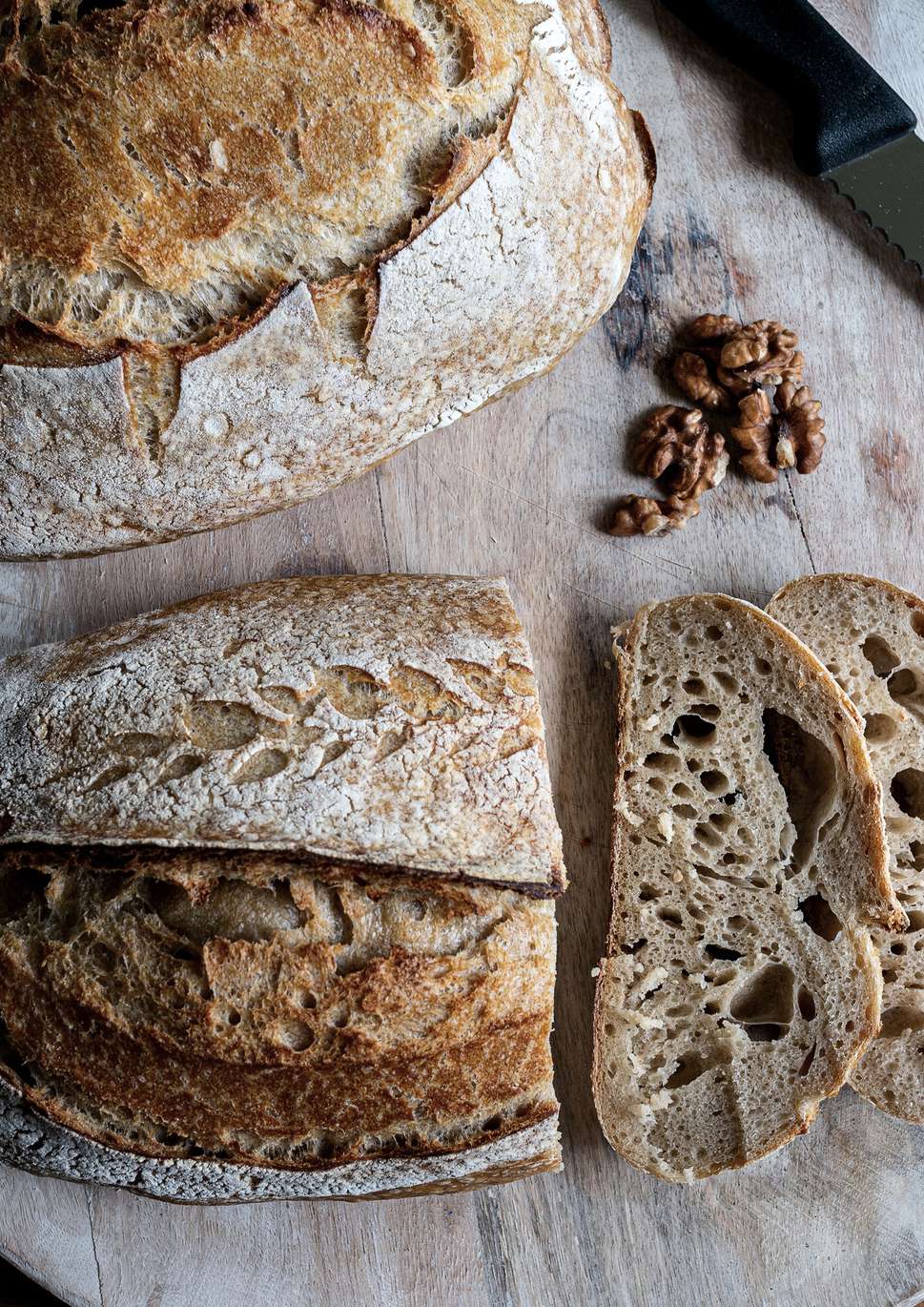 Pães de fermentação natural fatiados sobre tábua de madeira